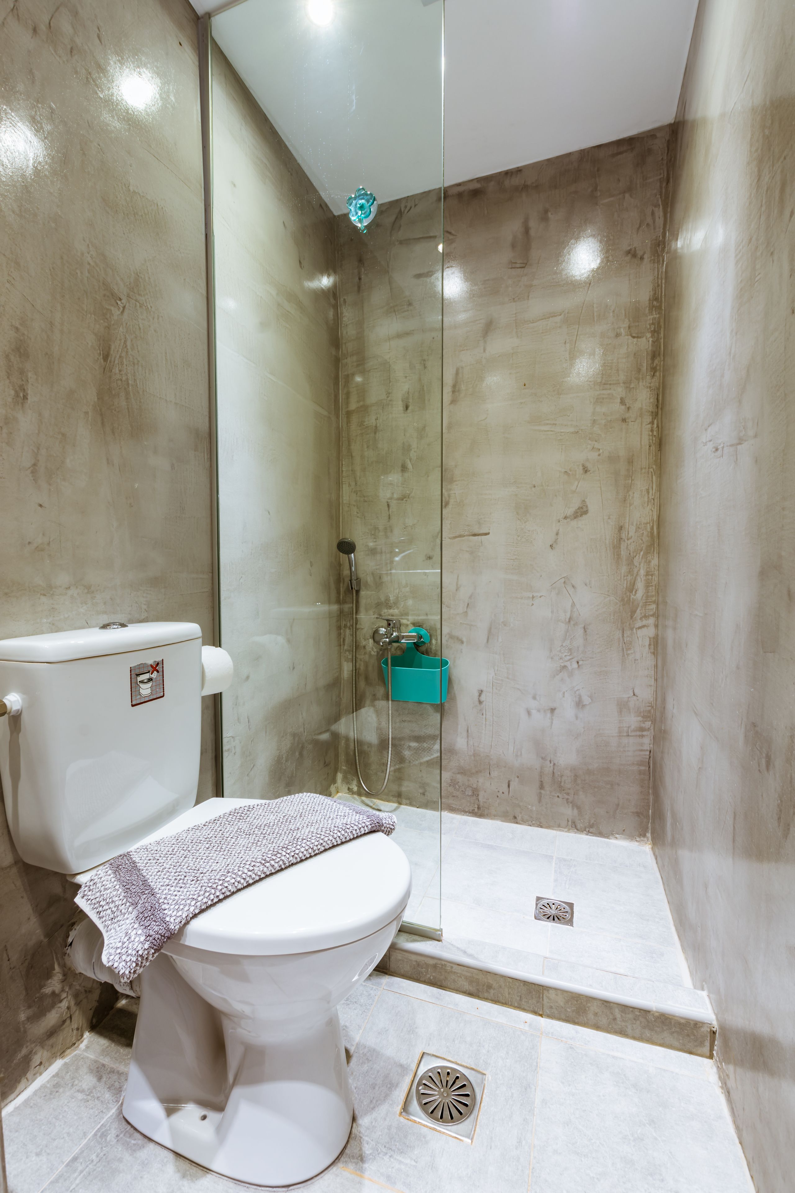 A bathroom with a toilet, shower, and a towel on the seat.