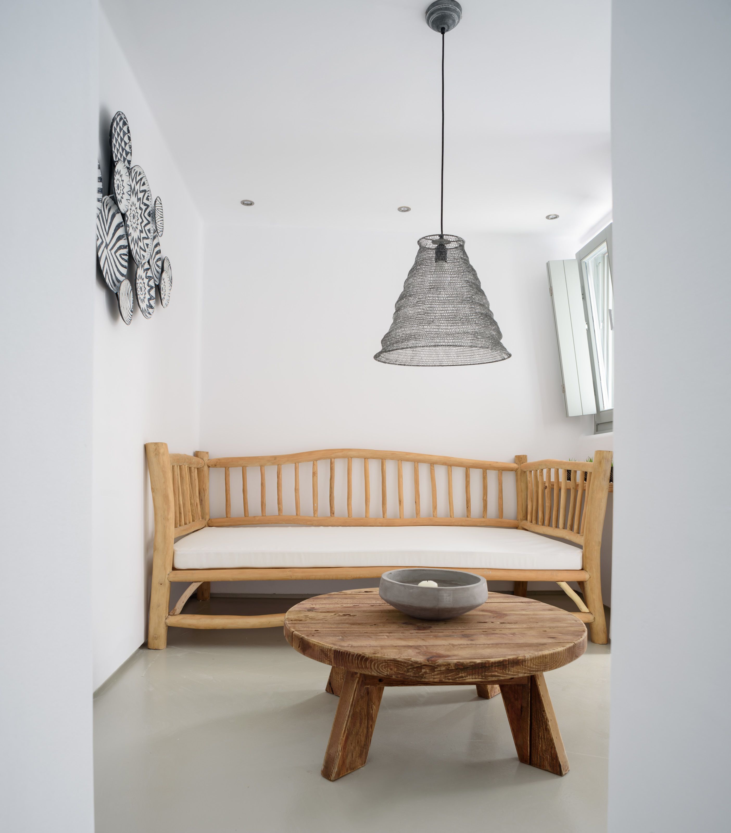 Una sala de estar moderna con un sofá de madera, una mesa redonda de madera y una lámpara colgante.