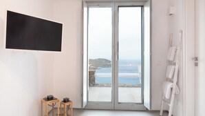 Un baño moderno con un amplio cerramiento de vidrio corredera que da a un balcón con vista al mar.