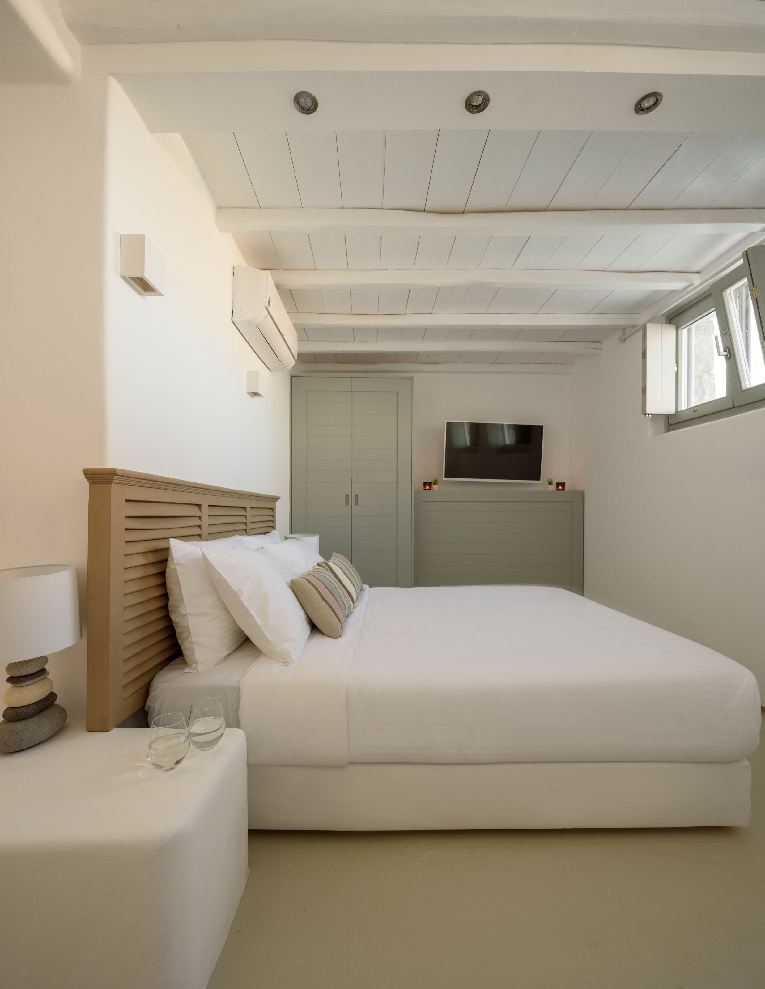 Een slaapkamer met een groot bed, een tv erboven en een kledingkast.