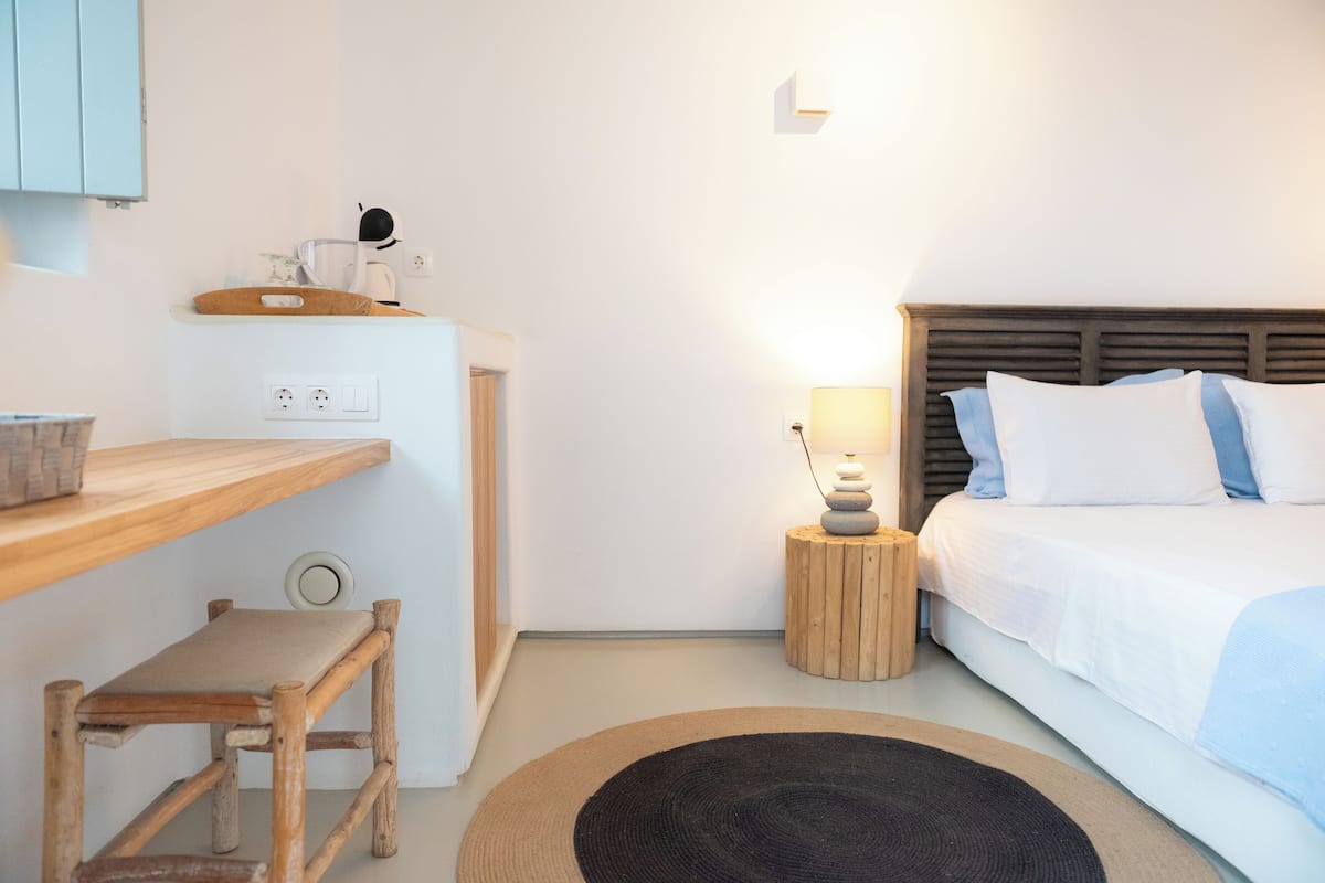 A bedroom with a bed, bedside table, lamp, and a small stool.