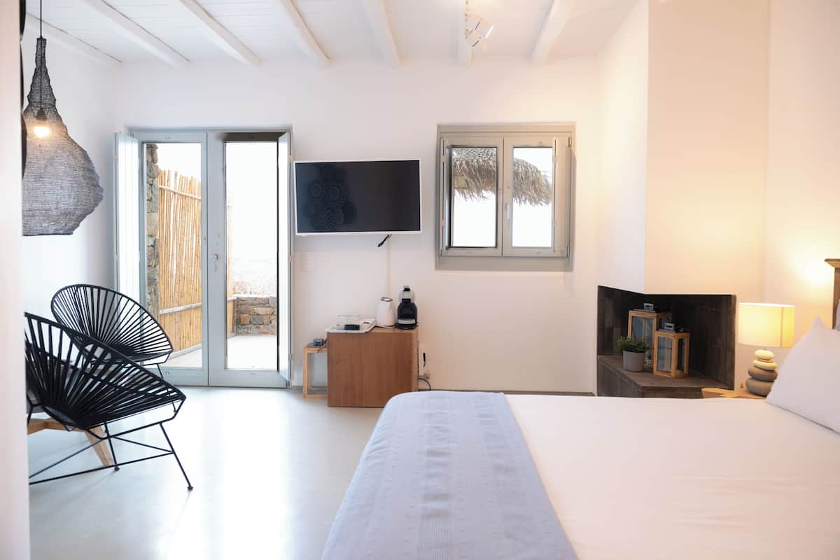 A bedroom with a bed, a TV, a chair, a desk, and a window.