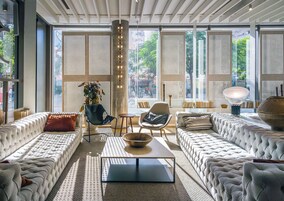 Una sala de estar moderna con un ventanal grande, un pilar central y una variedad de opciones de asientos, incluyendo sofás y sillones.