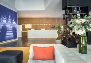 Un moderno vestíbulo de hotel con mostrador de recepción, zona de estar y una gran pantalla instalada en la pared.