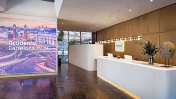 A modern reception area with a digital display of Barcelona 1929, a reception desk, and a wooden wall.