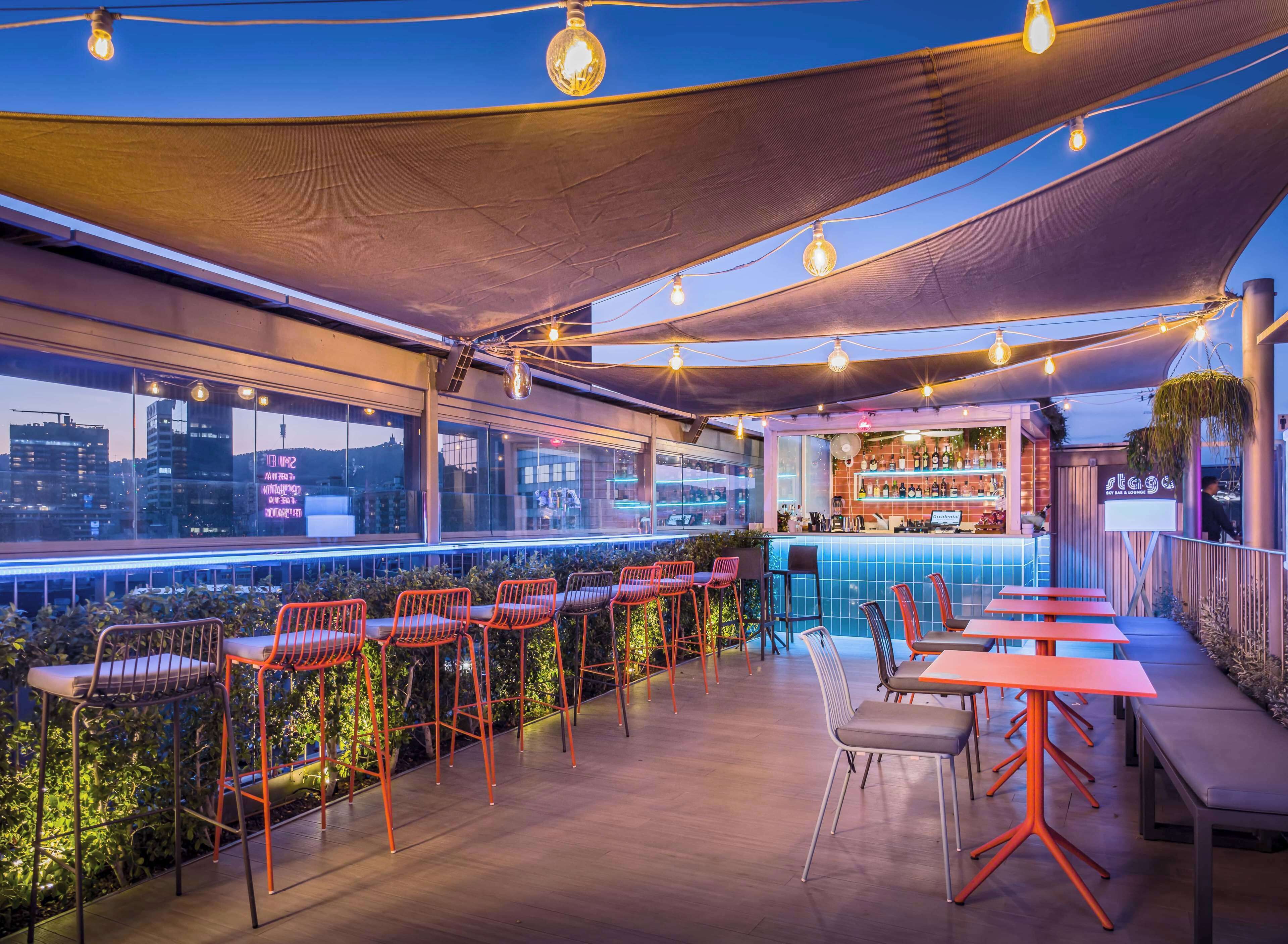 An outdoor bar area with seating, a bar counter, and a city view.