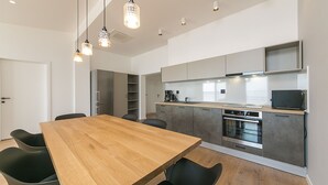 A modern kitchen with a wooden dining table, black chairs, and pendant lights. - Apartment Juric (Brela)
