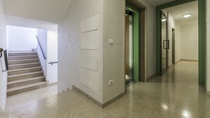 Ein Flur mit Treppe, einer grüngesäumten Tür und einer Wand mit drei weißen Feldern.