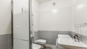 Ein modernes Badezimmer mit Duschkabine aus Glas, Toilette, Waschbecken und Handtuchhalter.