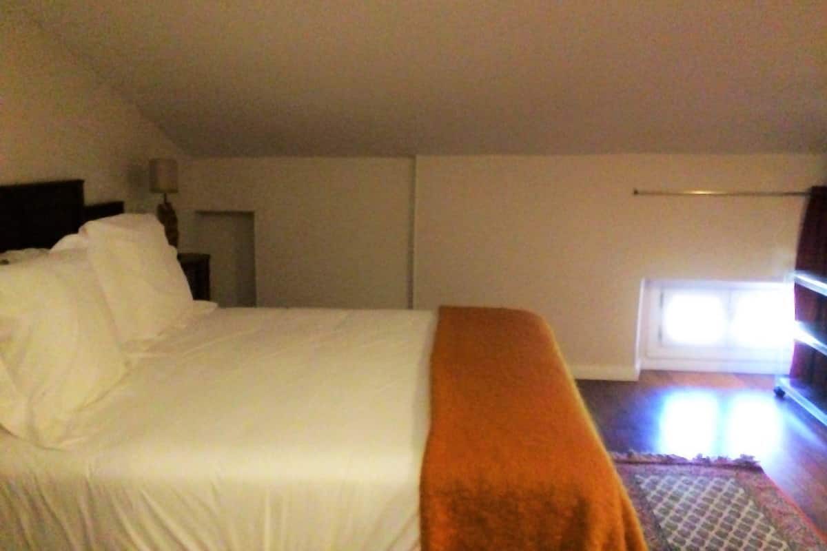 Une chambre à coucher avec un lit, une table de chevet, une lampe et une fenêtre.