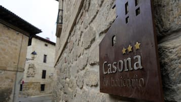 Una señal con la inscripción "Casona del boticario" colocada en un muro de piedra.