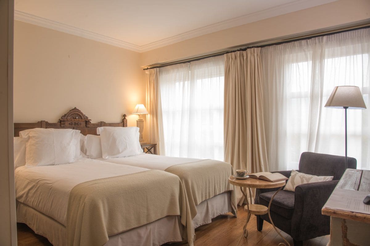 Ein Hotelzimmer mit zwei Betten, einem kleinen Tisch, einem Stuhl und einer Lampe.