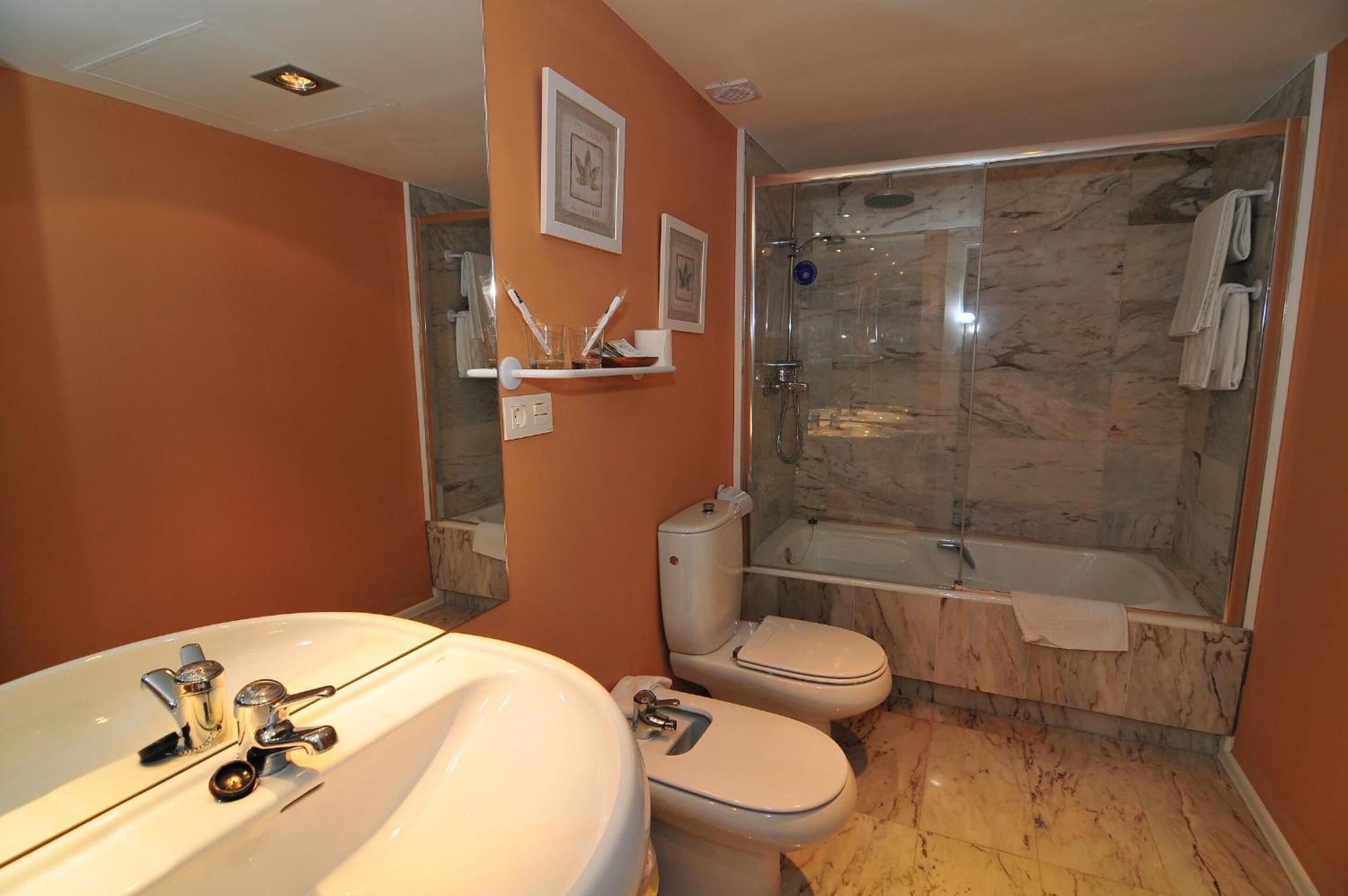 Un baño con ducha de mármol, bañera, inodoro y lavabo.