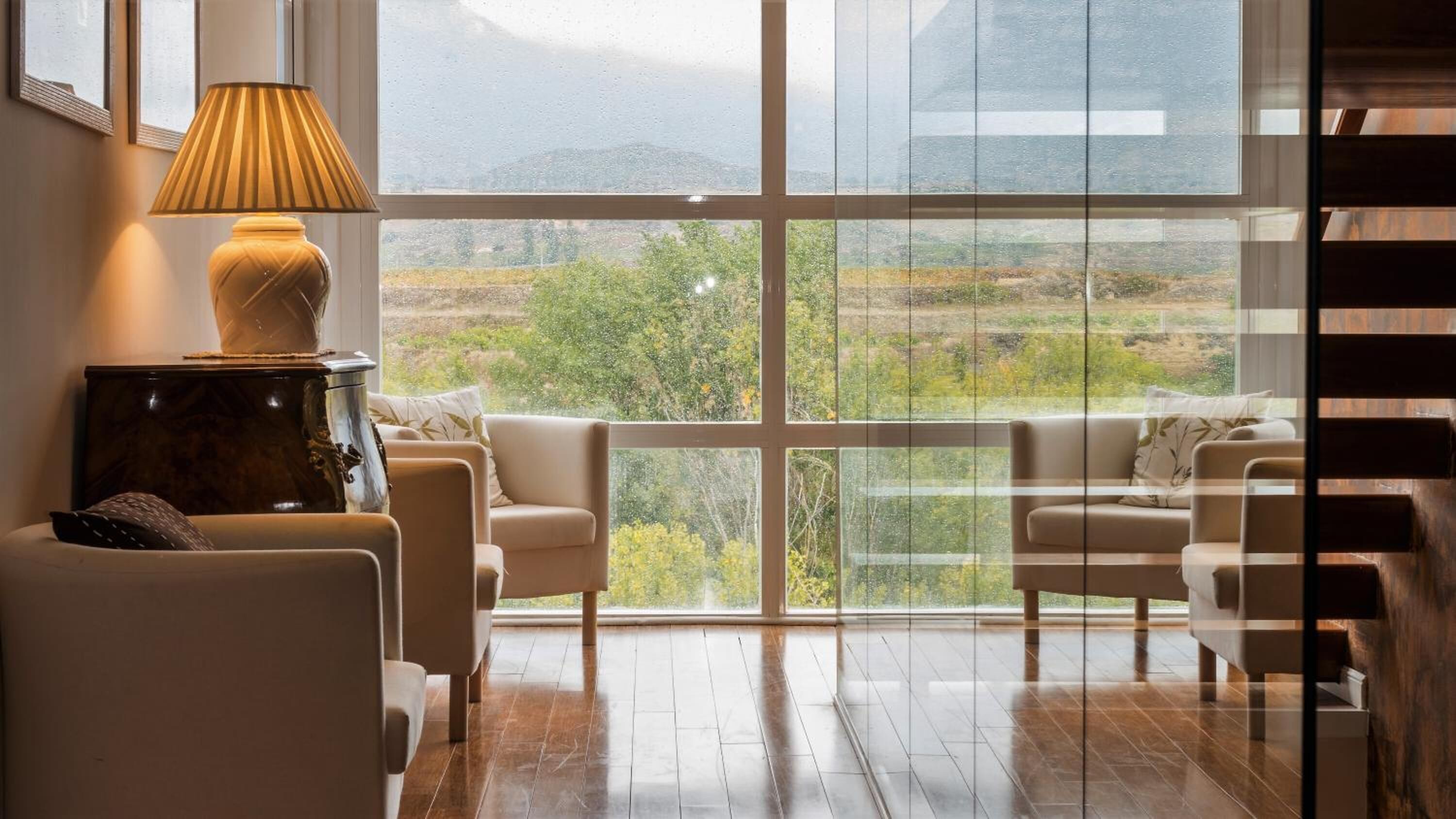 Un amplio salón con un ventanal grande, una lámpara y un sofá.