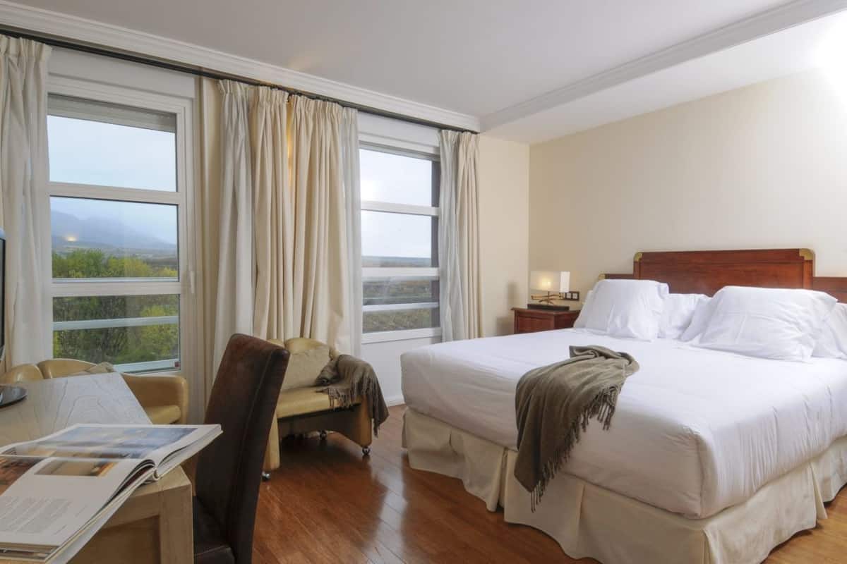 Une chambre d’hôtel avec un grand lit, un bureau avec une chaise, une télévision et une vue sur l’extérieur.