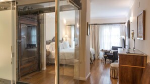 A hotel room with a sliding door leading to a balcony, a bed, a desk, and a chair.