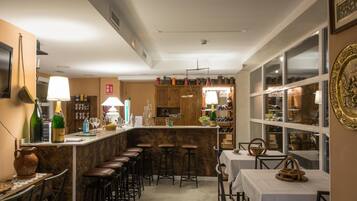 Una zona de bar con taburetes, una barra con botellas y un comedor con mesas y sillas.