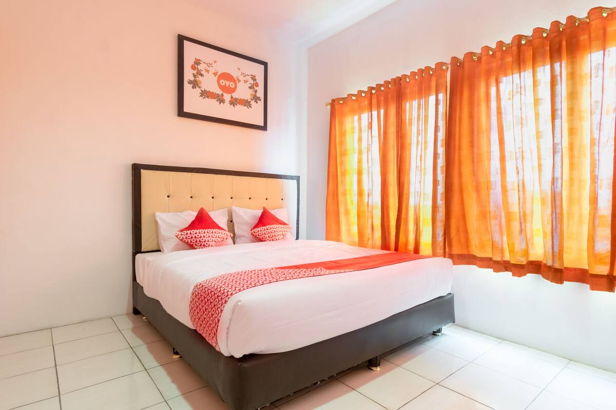 A neatly made bed with a headboard, two pillows, and a blanket.