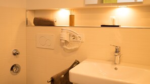 A bathroom with a white sink, a towel rack, a hairdryer, and a mirror.