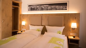 Uma cama de casal com duas mesas de cabeceira, uma cabeceira de madeira, um quadro emoldurado acima da cama e um guarda-roupa de madeira à esquerda.