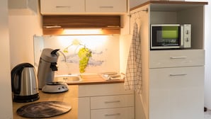 Uma cozinha compacta com chaleira, micro-ondas e pia.