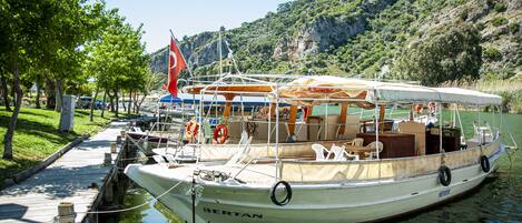 A boat docked at a pier with a mountainous backdrop.