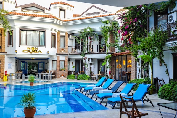 Relax by the pool surrounded by lush greenery and comfortable lounge chairs.