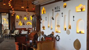 Tunnelmallinen oleskelualue, jossa on puuhuonekaluja, koristeellisia seinävalaisimia ja kyltti, jossa lukee: ”NIL LOUNGE”.