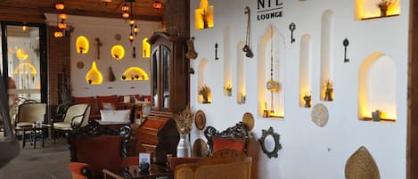 Un'accogliente area relax con arredi in legno, applique decorative e un cartello con su scritto 'NIL LOUNGE'.