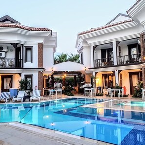 A pool area with a clear pool, lounge chairs, and a covered seating area. - Dalyan Hotel Nish Caria (Ortaca)