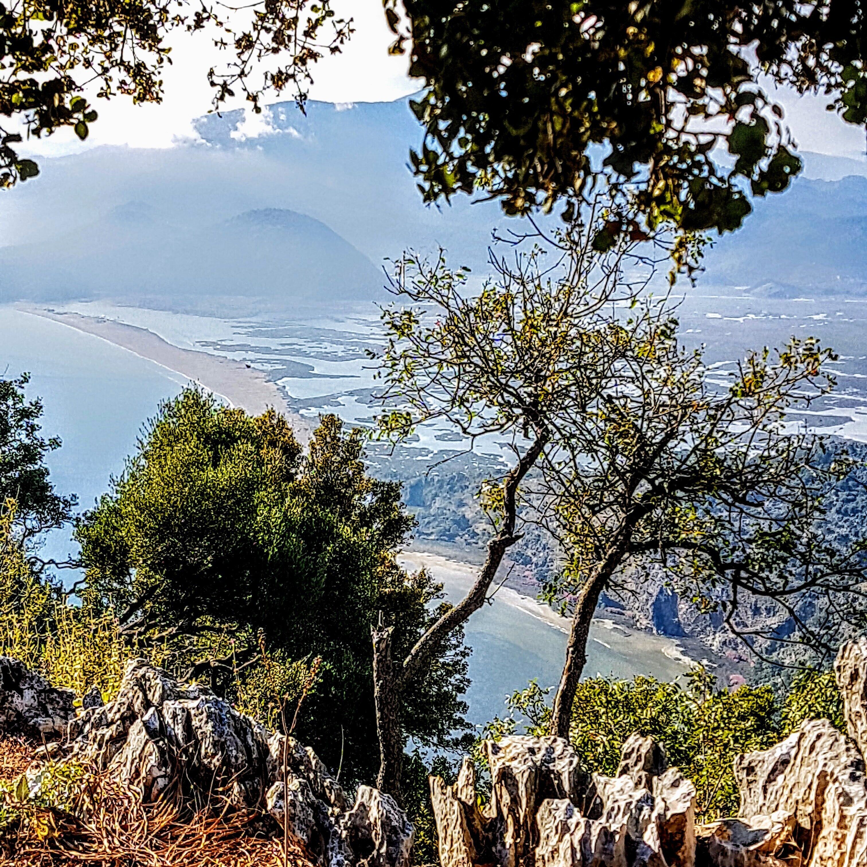 Un paisaje montañoso con una vista despejada de un cuerpo de agua, árboles y terreno rocoso.