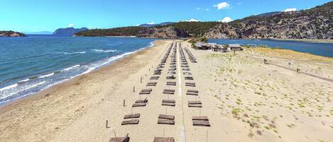 Una playa con filas de tumbonas y un camino pavimentado que conduce al agua.