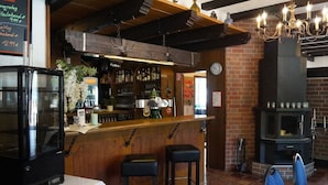 A bar area with a wooden counter, stools, and a brick wall.