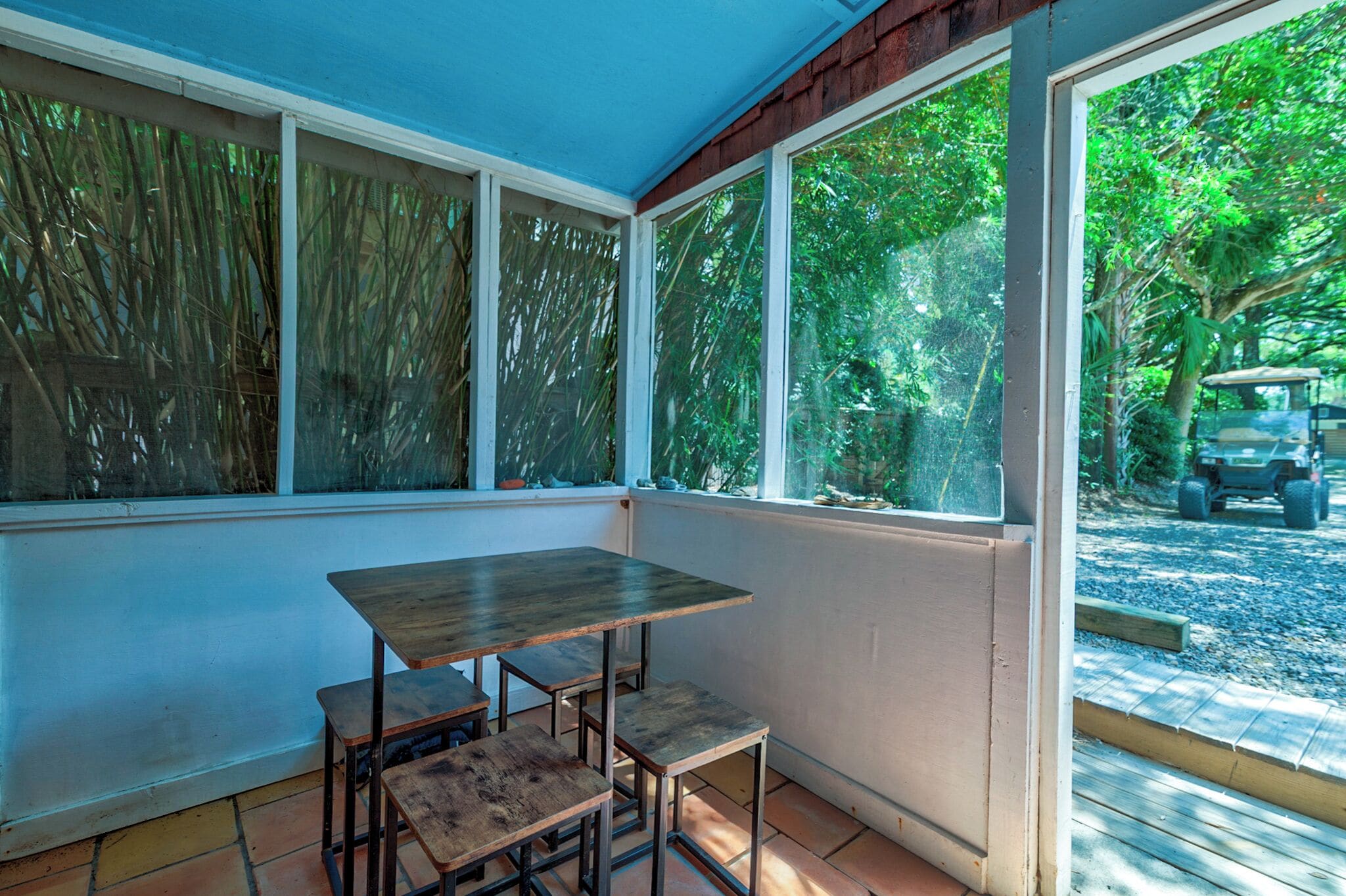 A sunroom with a table and benches, large windows, and a view of the outdoors.