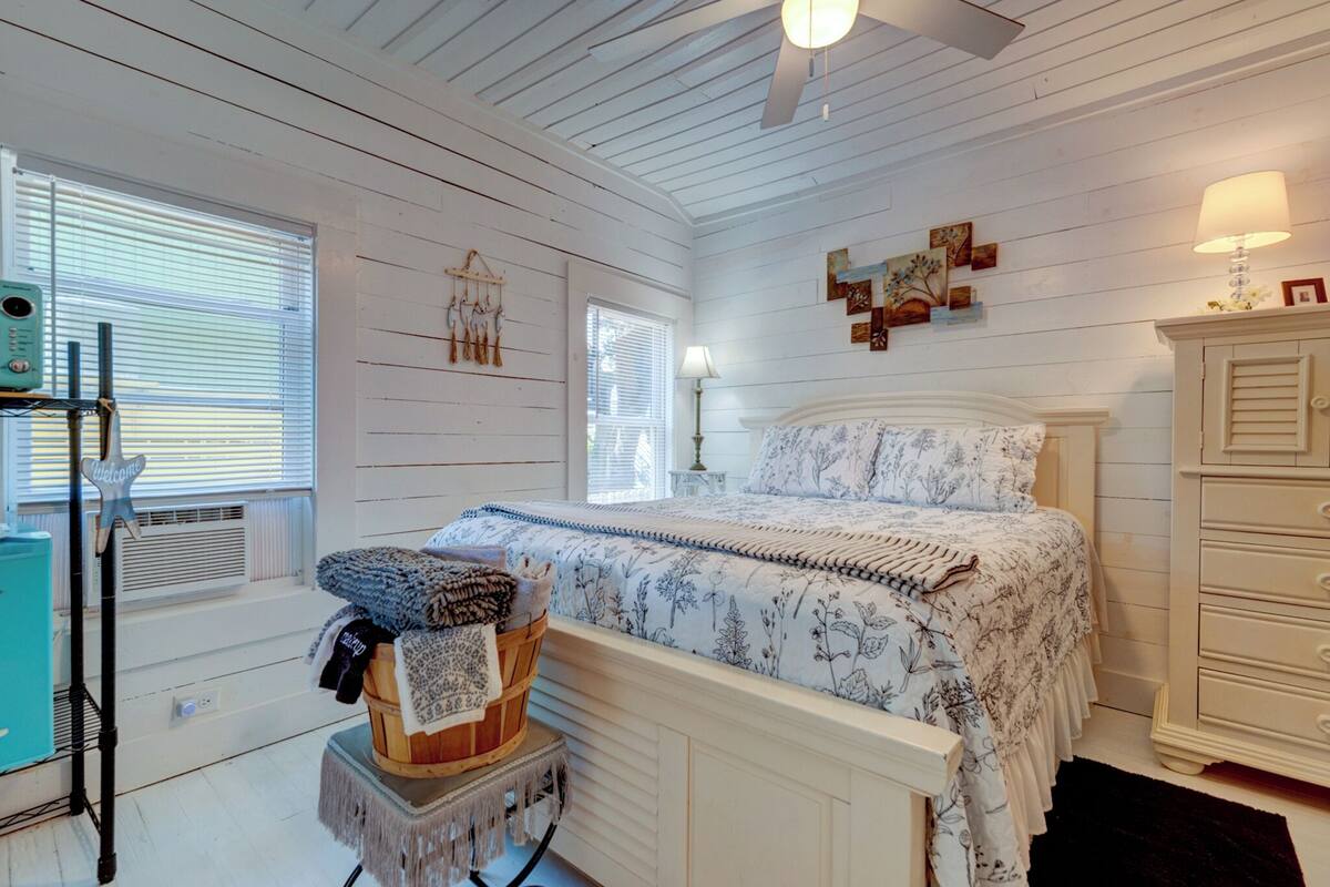 A bedroom with a bed, dresser, and a small table with a lamp.