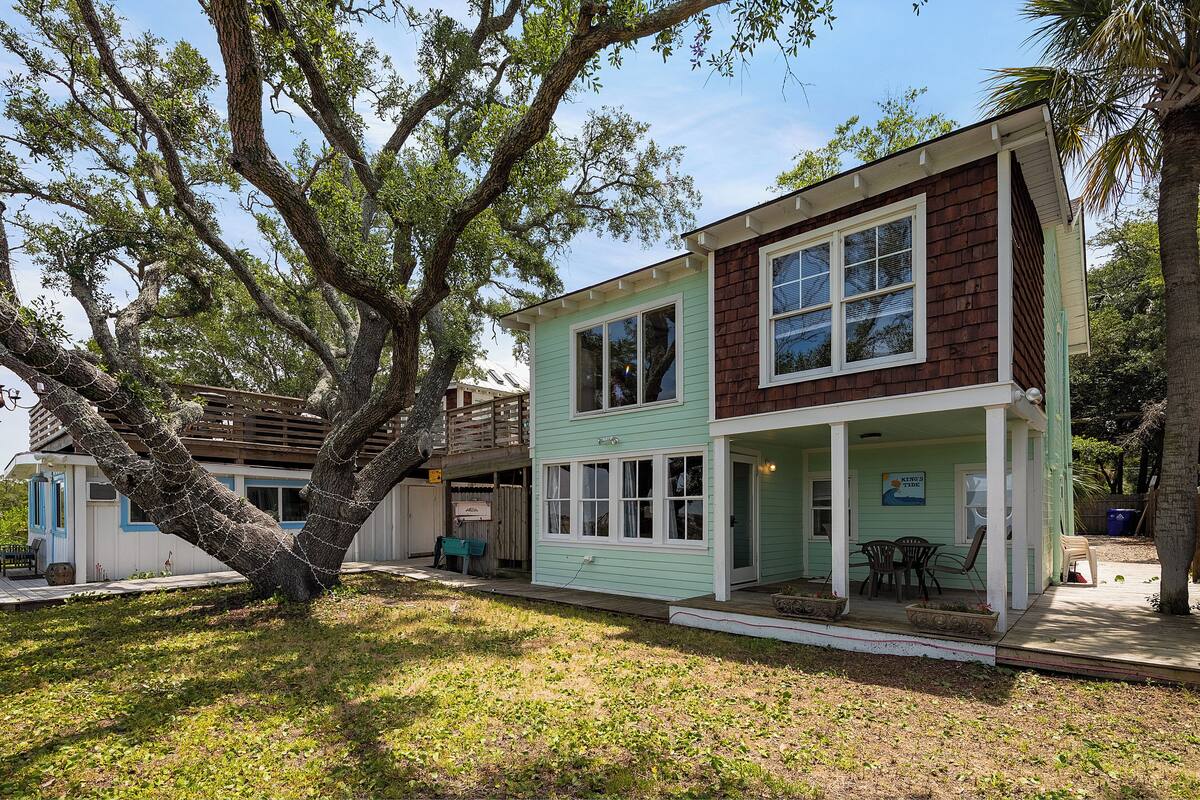 A two-story house with a porch, surrounded by trees.