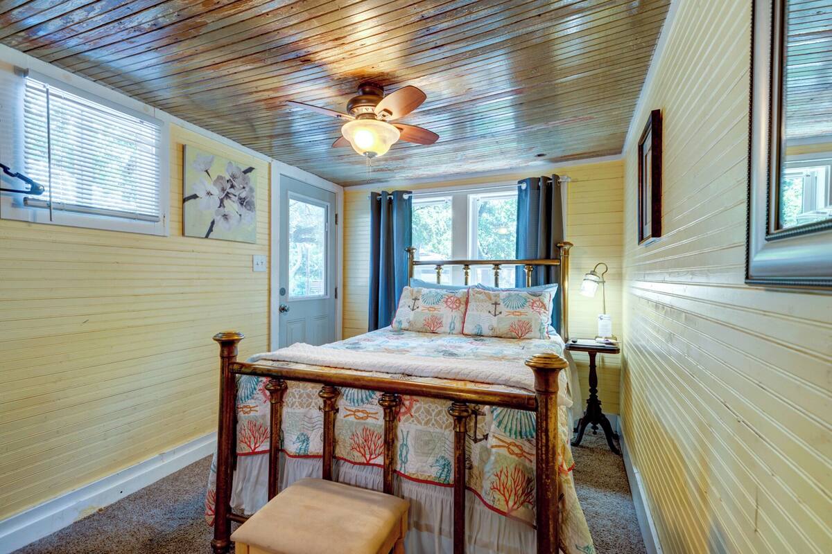 A bedroom with a wooden bed, a ceiling fan, and a window with curtains.