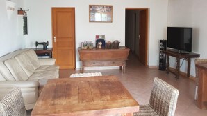 Una sala de estar con una mesa de madera, sofá y televisor.