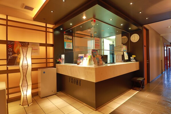 A reception desk with a clock, informational posters, and a small refrigerator. - Toyama Town Hotel 24 (Toyama)