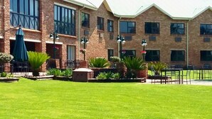 Edifício de tijolos com várias janelas e um gramado bem cuidado.