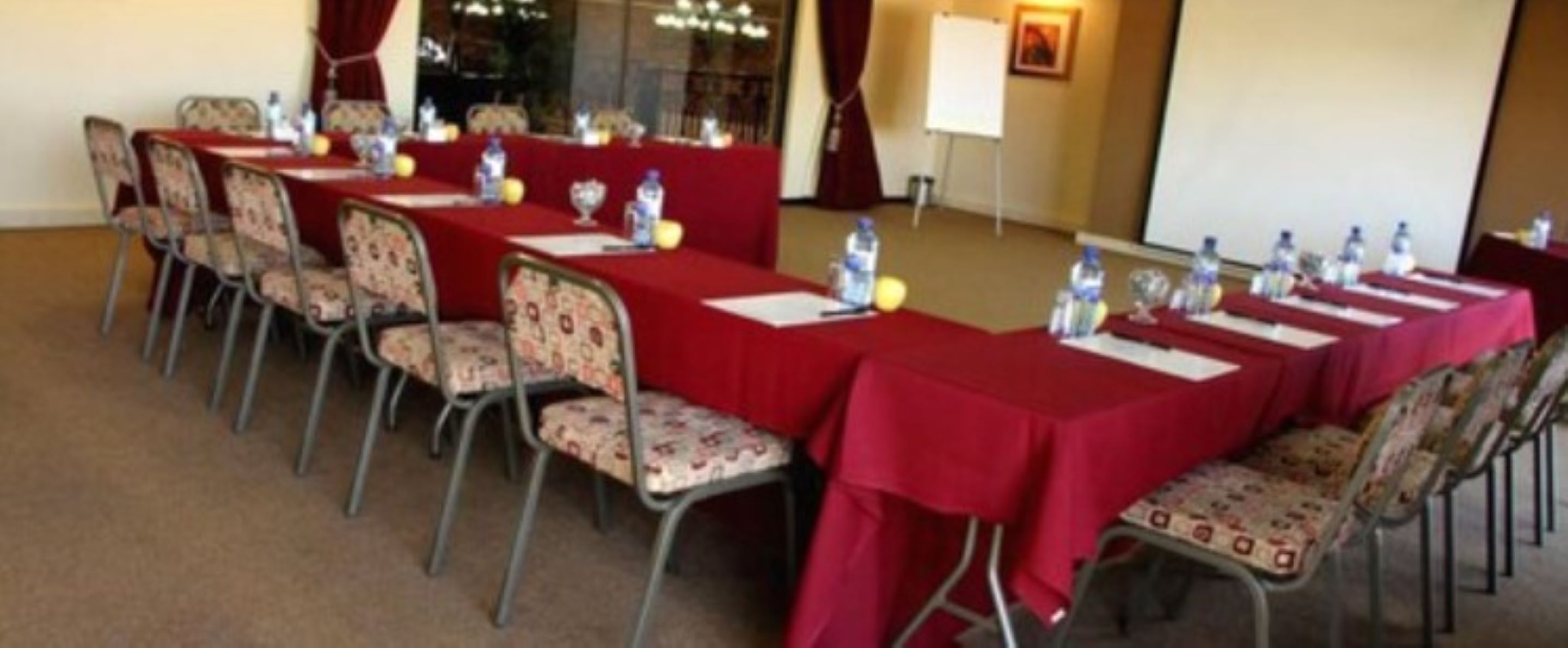 A conference room with long tables, chairs, and water bottles.
