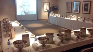 Sala de conferência com uma mesa comprida montada para uma reunião, com várias tigelas e garrafas de água.