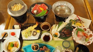 Variedad de platos japoneses, como sushi, sashimi y tempura, servidos sobre una mesa de madera con palillos y pequeños recipientes de salsa de soja.