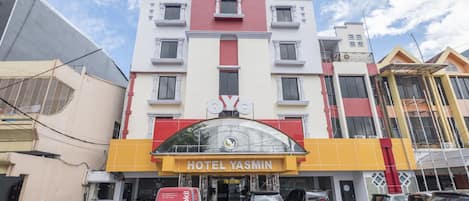 A multi-story hotel with a prominent 'HOTEL YASMIN' sign, featuring a modern architectural design with a red and yellow facade.