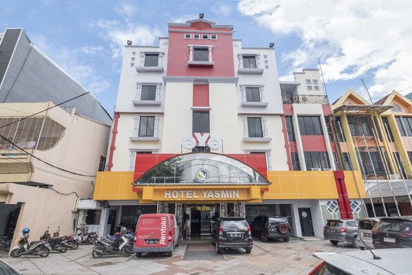 A multi-story hotel with a prominent 'HOTEL YASMIN' sign, featuring a modern architectural design with a red and yellow facade. - Collection O 637 Yasmin Hotel (Makassar)