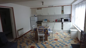 A compact kitchen with white cabinets, a tiled backsplash, a dining table with chairs, and a microwave. - gentian up to 4 people (Ferrières-Saint-Mary)