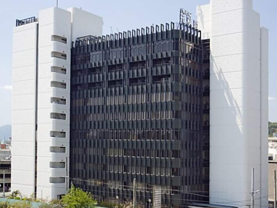 A modern building with a grid-like facade, multiple windows, and a flat roof.