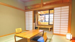 Ein traditioneller japanischer Raum mit Tatami-Boden, einem niedrigen Holztisch, einem Stuhl und Shoji-Schirmen.