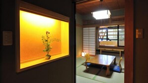 Ein traditioneller japanischer Raum mit Tatami-Bodenbelag, einem niedrigen Tisch und einem Shoji-Bildschirm.