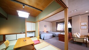 Ein traditioneller japanischer Raum mit Tatami-Boden, einem niedrigen Holztisch, einem Futonbett und einem Fernseher.